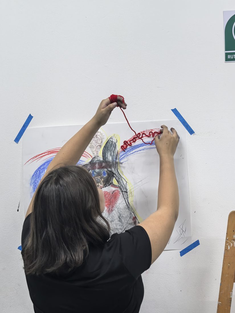 Participante interviniendo su dibujo con estambre rojo