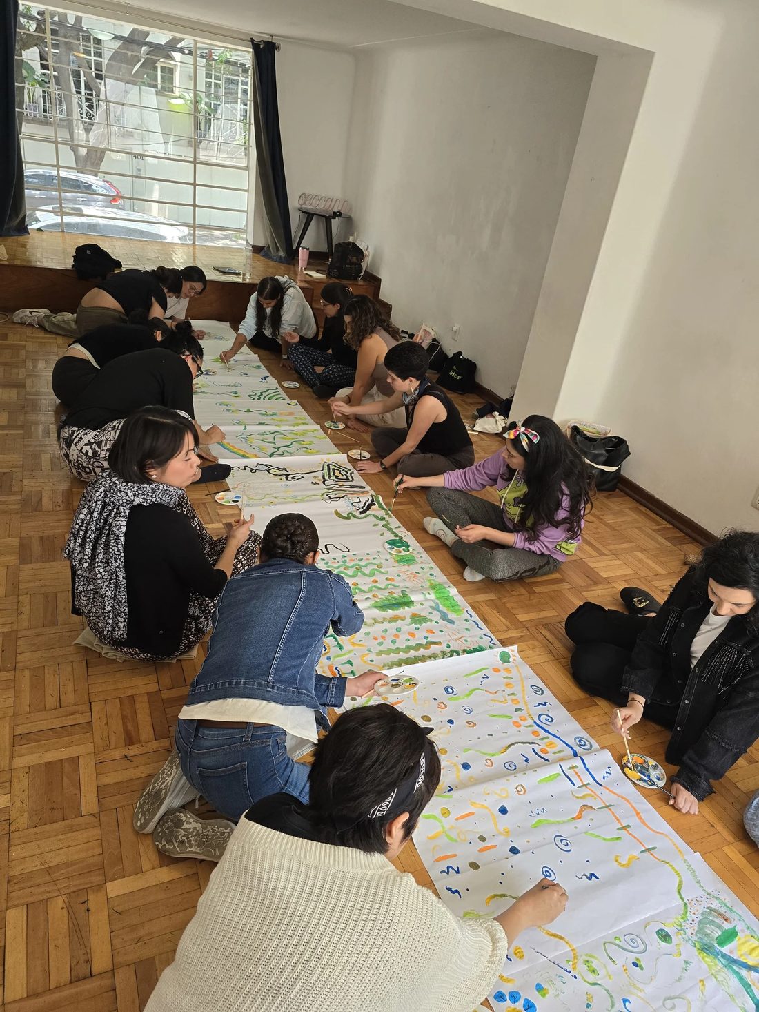 Grupo pintando un mural colectivo sobre el piso