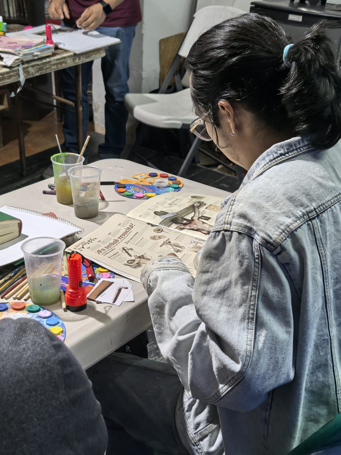 Participante del taller trabajando con materiales de arte sobre una mesa
