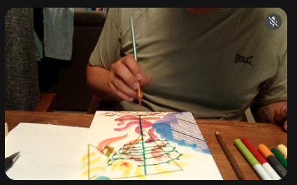 Participante pintando con acuarelas durante una sesión en línea