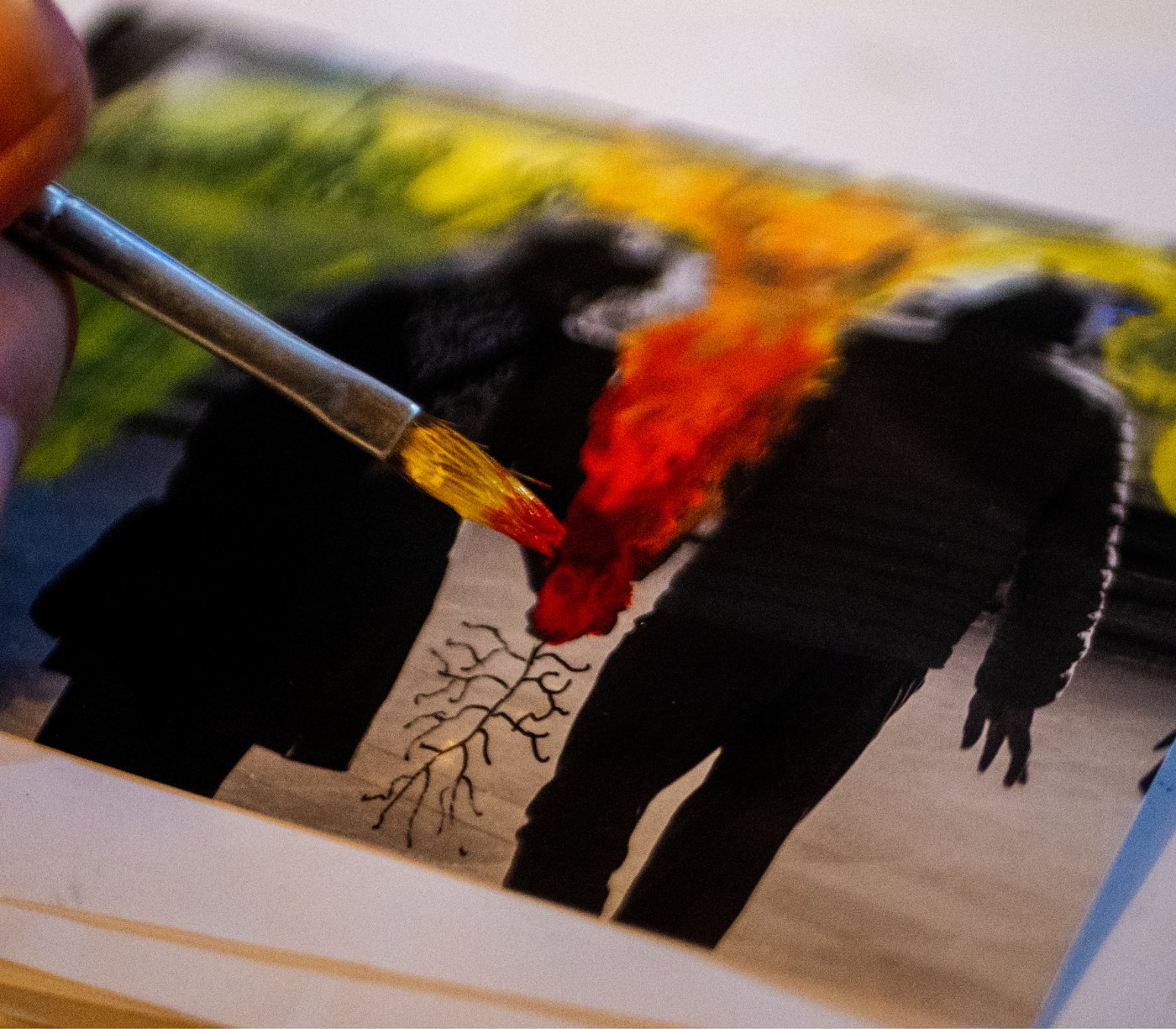 Mano interviniendo una fotografía impresa con pincel y pintura roja